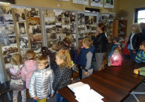 Grupa dzieci ogląda galerię zdjęć o dawnej wsi.